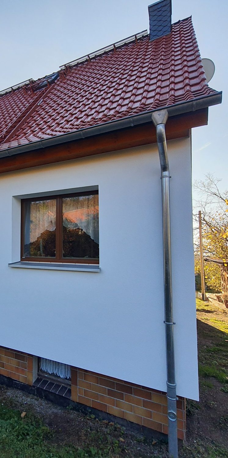 Eine Wandöffnung ist mit einem Brett eingelattet. Die Leibung wird von Hand verputzt und die Oberfläche abgezogen.