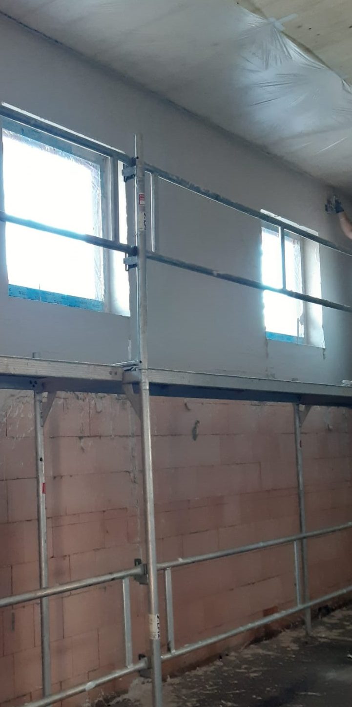 Mit dem Gerüst konnte der obere Teil der Wand innen bereits verputzt werden. Unten sieht man die rohen Mauerziegel der Außenwand.